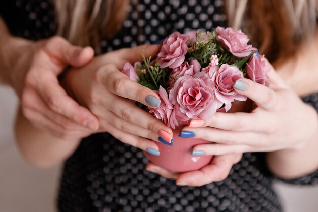 Abbracciando l'uomo e la donna tengono insieme le rose in una tazza cremisi.