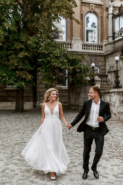 Abbracciare dello sposo e della sposa nella vecchia via della città. Sposi innamorati. Abito di strass di lusso.