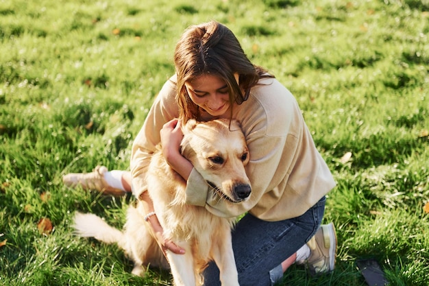 Abbracciare l'animale La giovane donna fa una passeggiata con il Golden Retriever nel parco