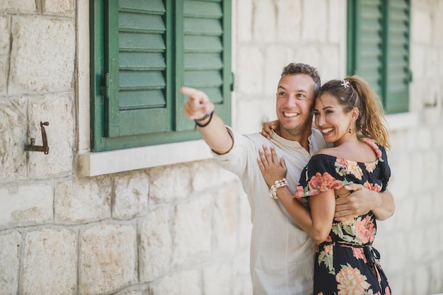 Abbracciare le coppie felici divertendosi e indicando qualcosa mentre si cammina attraverso la vecchia città mediterranea.