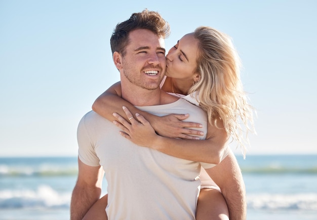 Abbraccio d'amore sulla spiaggia e bacio di coppia in una fuga romantica per un appuntamento o un'avventura nella natura all'aperto per la pace, la libertà e il divertimento Oceano mare cielo blu e uomo e donna sulle spalle durante le vacanze a Sydney in Australia