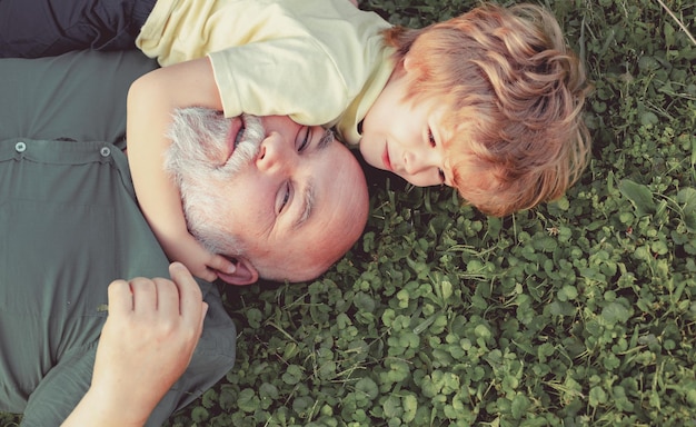 Abbraccio e abbraccio sull'erba verde nonno e nipote felice uomo anziano nonno con carino littl