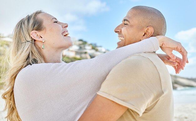 Abbraccio sulla spiaggia e amore interrazziale della coppia con un sorriso felice e allegro goditi le vacanze in Brasile Cura della felicità e romanticismo degli innamorati che si abbracciano per un momento gioioso durante le vacanze sull'oceano