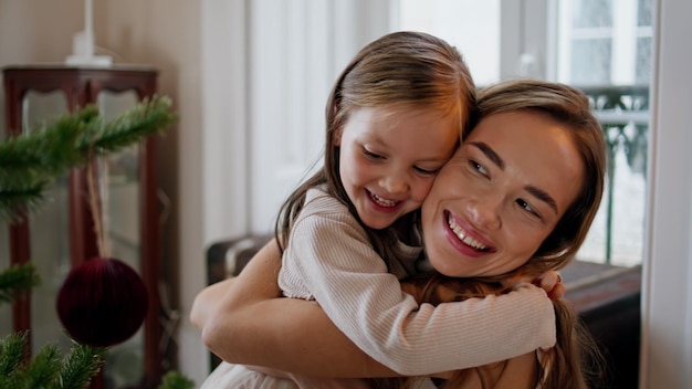 Abbraccio tenero della figlia della madre Ritratto del posto dell'albero del nuovo anno Famiglia carina che abbraccia