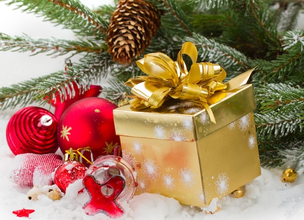 Abete e decorazioni natalizie rosse e confezione regalo sul bianco della neve