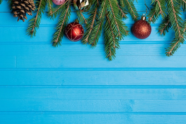 Abete, rami di abete rosso e giocattoli dell'albero di Natale su legno blu con lo spazio della copia