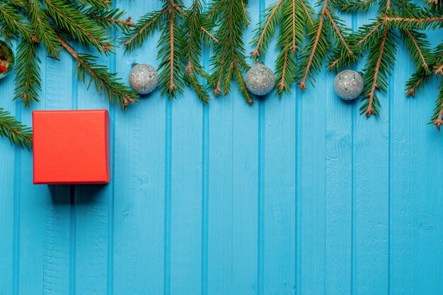 Abete, rami di abete rosso, giocattoli dell'albero di Natale, confezione regalo su legno blu