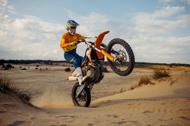 Abile motociclista professionista che fa acrobazie in moto. Motociclista che fa trick difficili e pericolosi nel deserto