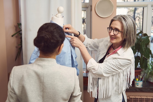 Abili team di sarti stilisti di moda provano la nuova collezione di camicia da donna su un manichino e lavorano per migliorare lo stile e il design dei nuovi capi nell'atelier sartoriale