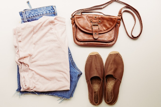 Abiti ideali per outfit estivi: una camicia, jeans, una borsa, scarpe. Vista dall'alto.