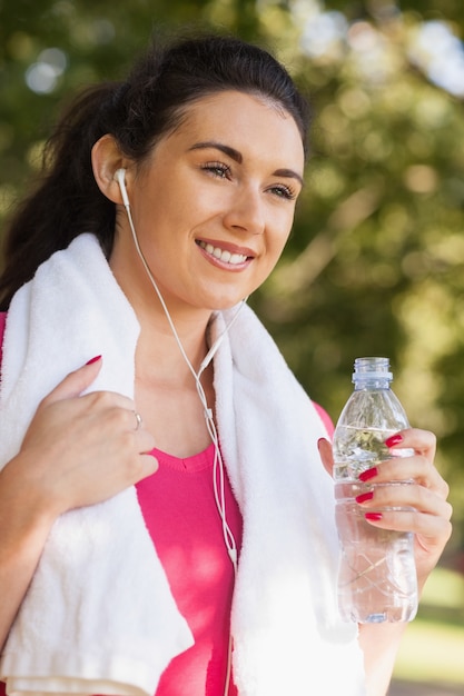 Abiti sportivi d&#39;uso della donna sportiva felice che tengono una bottiglia