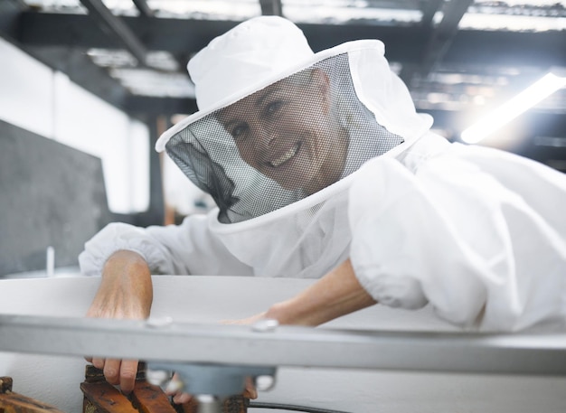 Abito da apicoltore donna e produzione di produzione di miele e processo in officina o magazzino Sorriso di allevatore di api felice per il raccolto di ispezione dell'alveare e il mantenimento di piccole imprese