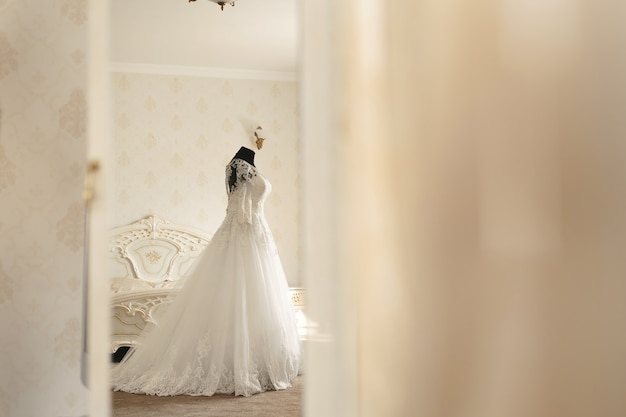 Abito da sposa chic e velo su un manichino nella sala riunioni della sposa. Vista attraverso la porta.