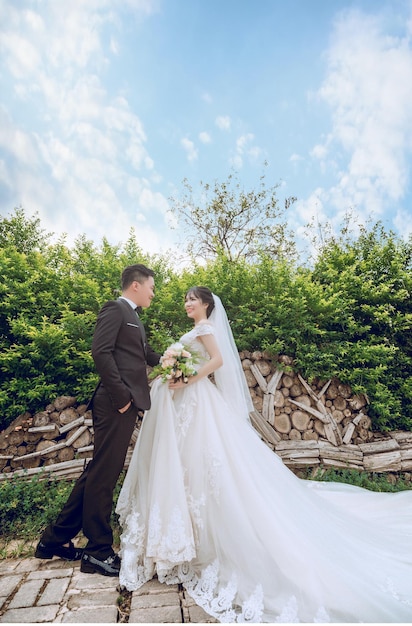 abito da sposa in piedi in giardino vicino a belle piante sorridenti