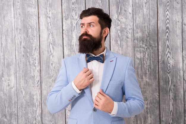 Abito da sposa romantico Barbiere in stile gentiluomo Il negozio di barbiere offre una gamma di pacchetti per lo sposo Concetto di negozio di barbiere Barba e baffi Ragazzo ben curato e bello hipster con la barba indossa lo smoking