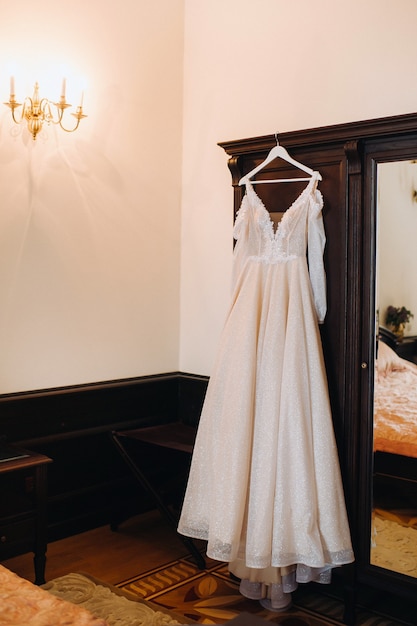 Abito da sposa vintage appeso a un gancio di legno.