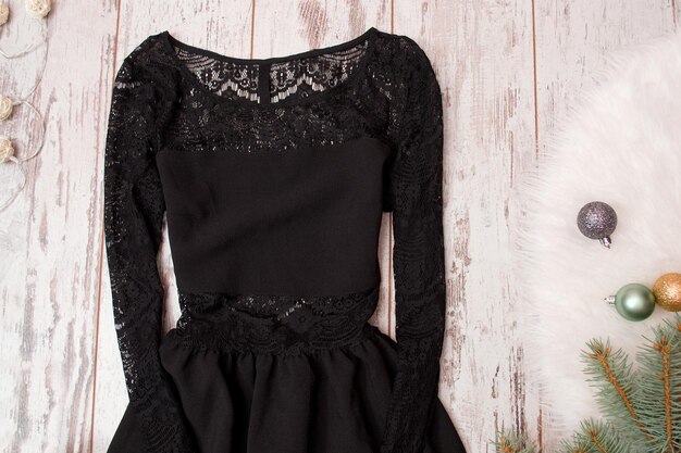 Abito nero con pizzo su un ramo di furtree di fondo in legno con concetto di moda ornamenti