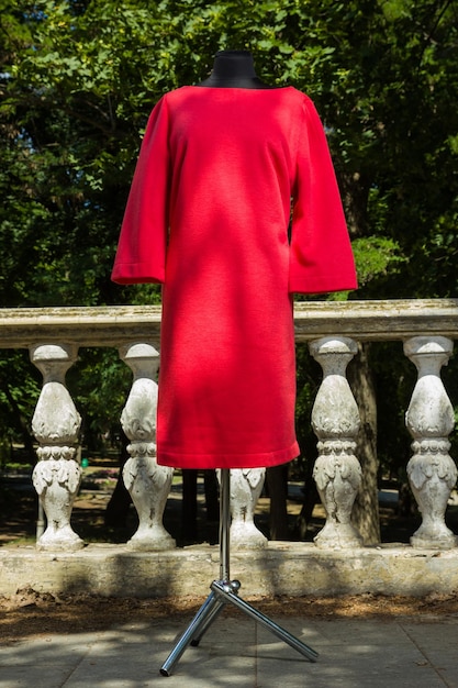 Abito rosso su manichino Abito da donna autunnale con maniche lunghe Abbigliamento femminile taglio dritto su sfondo di colonne di pietra Sartoria individuale