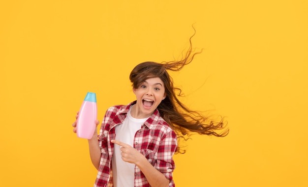 Abitudini quotidiane e cura della persona. presentazione del prodotto cosmetico. bellezza. il bambino usa il gel doccia. ragazza teenager felice con la bottiglia di shampoo. shampoo per capelli in salone. bambino con balsamo. lunghi capelli ricci.