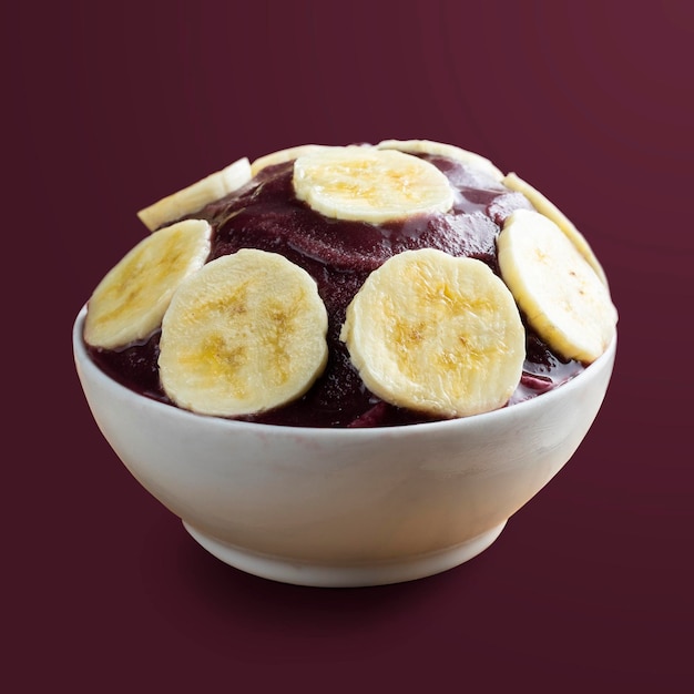 Acai Ciotola di gelato alla bacca di acai congelata brasiliana con fette di banana isolata su sfondo viola