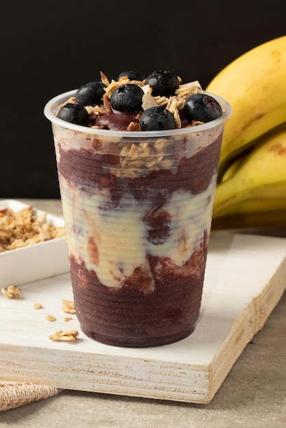 Acai congelato con muesli al latte condensato e mirtillo in un bicchiere di plastica