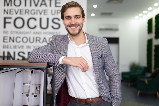Accattivante giovane uomo d'affari in giacca e cravatta con un sorriso in mezzo all'ufficio