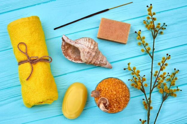 Accessori da bagno e spa piatti sulla scrivania in legno blu. Asciugamano arrotolato con conchiglia e sapone.