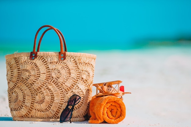 Accessori da spiaggia - borsa, cappello di paglia, occhiali da sole sulla spiaggia bianca