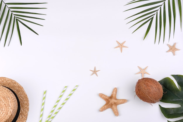 Accessori da spiaggia: cappello con conchiglie e stelle marine su sfondo bianco. Sfondo estivo