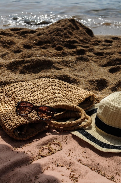 Accessori da spiaggia cappello di paglia borsa estiva occhiali da sole e orecchini su copriletto