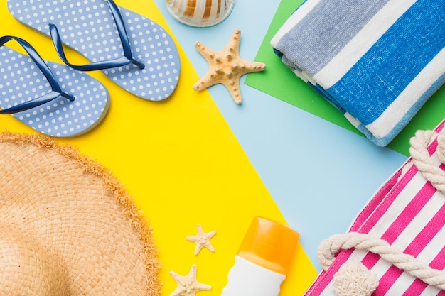 Accessori da spiaggia cappello di paglia e conchiglia su tavola colorata Sfondo estivo