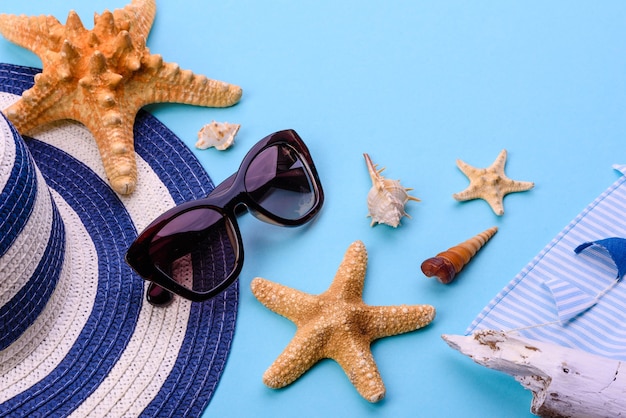 Accessori da spiaggia: occhiali e cappello con conchiglie e stelle marine. Sfondo estivo