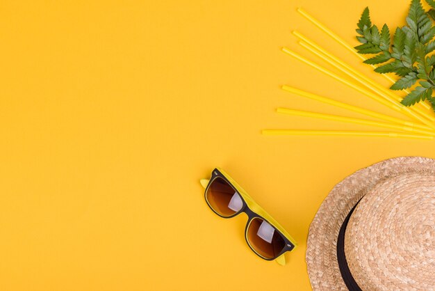 Accessori da spiaggia: occhiali e cappello con conchiglie e stelle marine su fondo colorato. Sfondo estivo