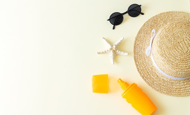 Accessori da spiaggia piatta laici e vista dall'alto di sfondo estivo. Cappello da sole, occhiali da sole, bottiglia di crema solare e stelle marine con spazio per le copie