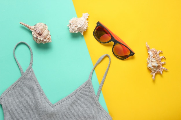 Accessori da spiaggia. T-shirt, occhiali da sole, crema solare, cockleshells. Vista dall'alto