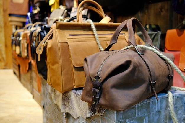 Accessori da uomo con borse in pelle marrone su tavolo di legno su sfondo muro