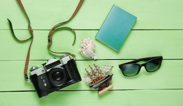 Accessori del viaggiatore, retro macchina fotografica sulla tavola di legno verde