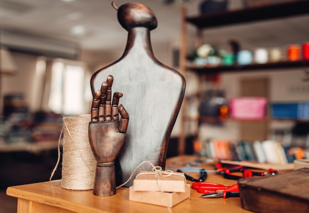 Accessori di ricamo, mano di legno e manichino sul tavolo, primo piano. Gioielli fatti a mano, interni di officina