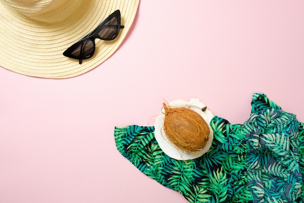 Accessori e cocco delle donne dell'estate piana di disposizione su fondo di rosa pastello con spazio per testo. Vista dall'alto concetto di viaggio o di vacanza. Sfondo estivo