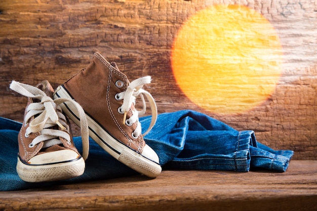 Accessori, jeans e scarpe da ginnastica su fondo in legno