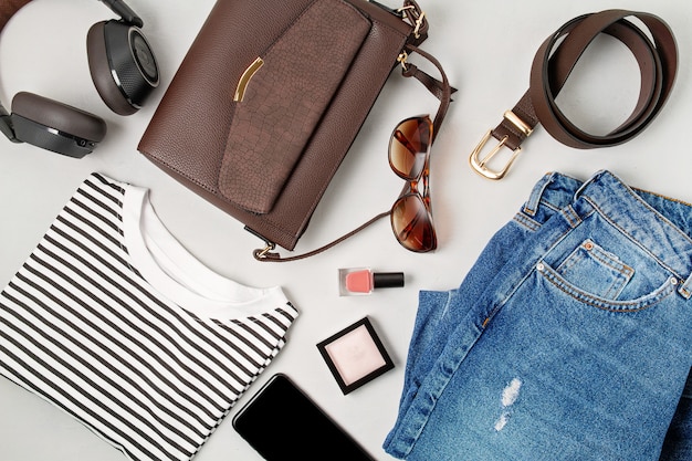 Accessori moda femminile, jeans, occhiali da sole, smart phone, auricolari e borsetta