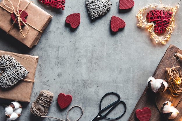 Accessori per confezioni regalo. Regali in carta artigianale su sfondo grigio. San Valentino, sorpresa e fiori di cotone