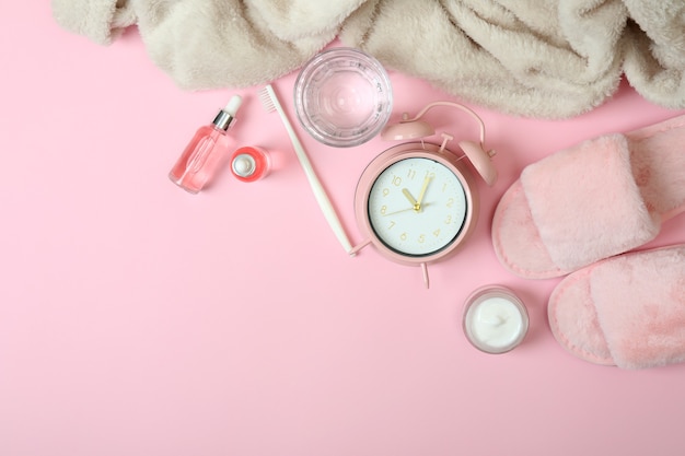 Accessori per la routine del sonno femminile su sfondo rosa