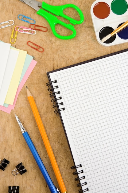 Accessori per la scuola e taccuino controllato sulla tavola di legno