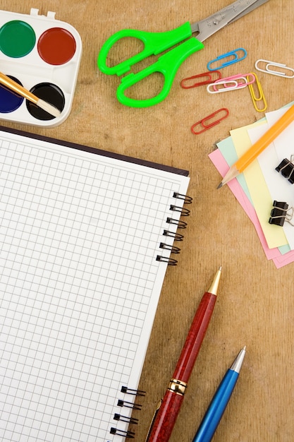 Accessori per la scuola e taccuino controllato sulla tavola di legno