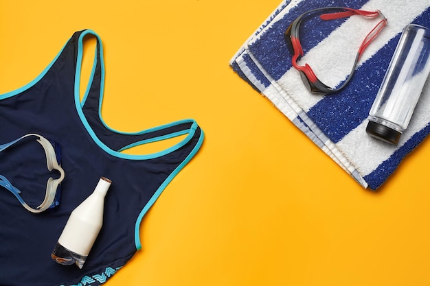 Accessori per piscine estive piatte su sfondo giallo Abbigliamento da spiaggia colorato