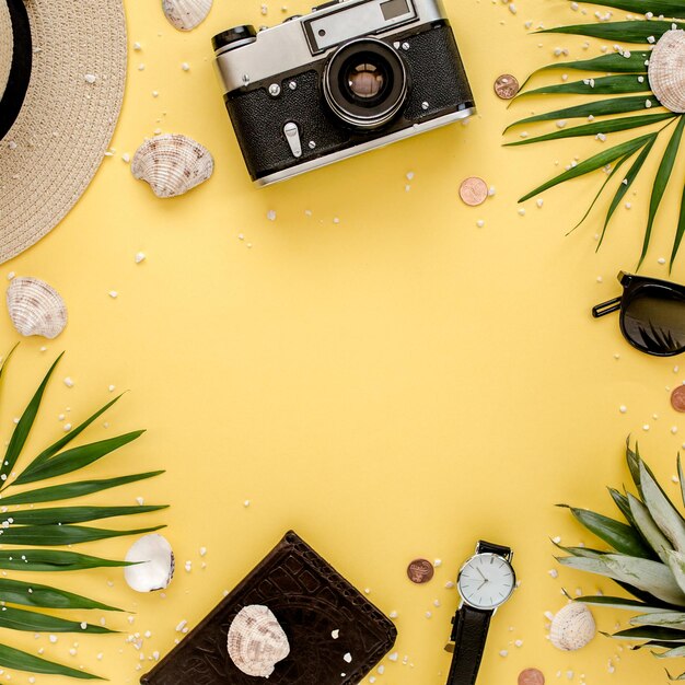 Accessori per viaggiatori rami di foglie di palma tropicali su sfondo giallo con spazio vuoto per il testo Sfondo estivo Vista dall'alto piatta