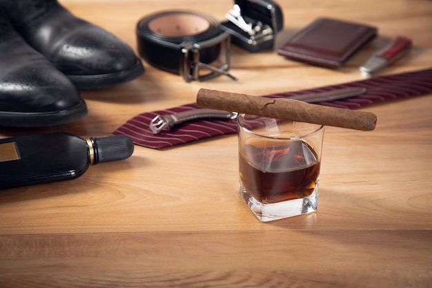 Accessori uomo con whisky e sigari sul tavolo