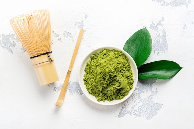 Accessori verdi del tè e della polvere del tè di matcha su fondo bianco