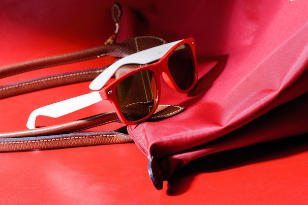 Accessorio donna primo piano occhiali da sole in plastica rossa su sfondo rosso